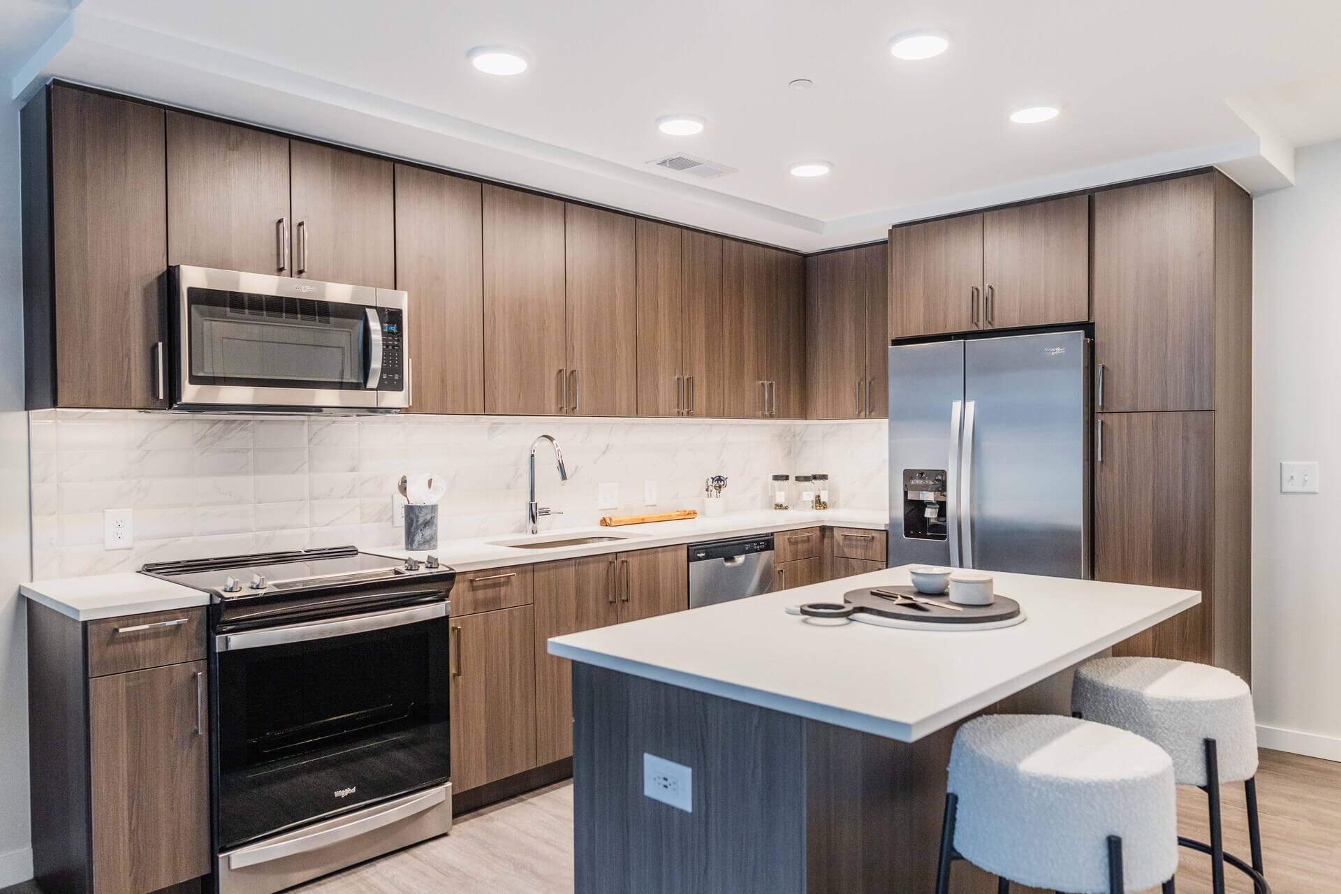Gourmet Kitchen And Dining Area With White Countertops, Mocha Espresso Cabinets, And Stainless Steel- Appliances