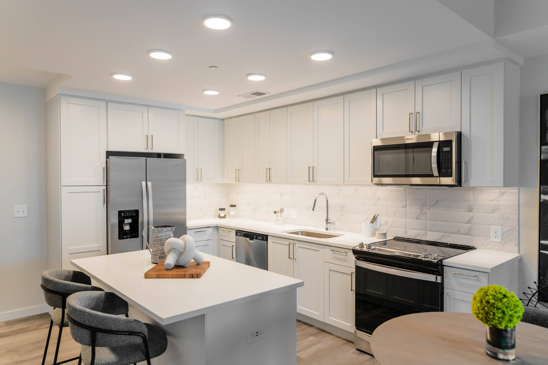 Gourmet Kitchen And Dining Area With White Countertops, Pearl Paneled Cabinets, And Stainless Steel- Appliances