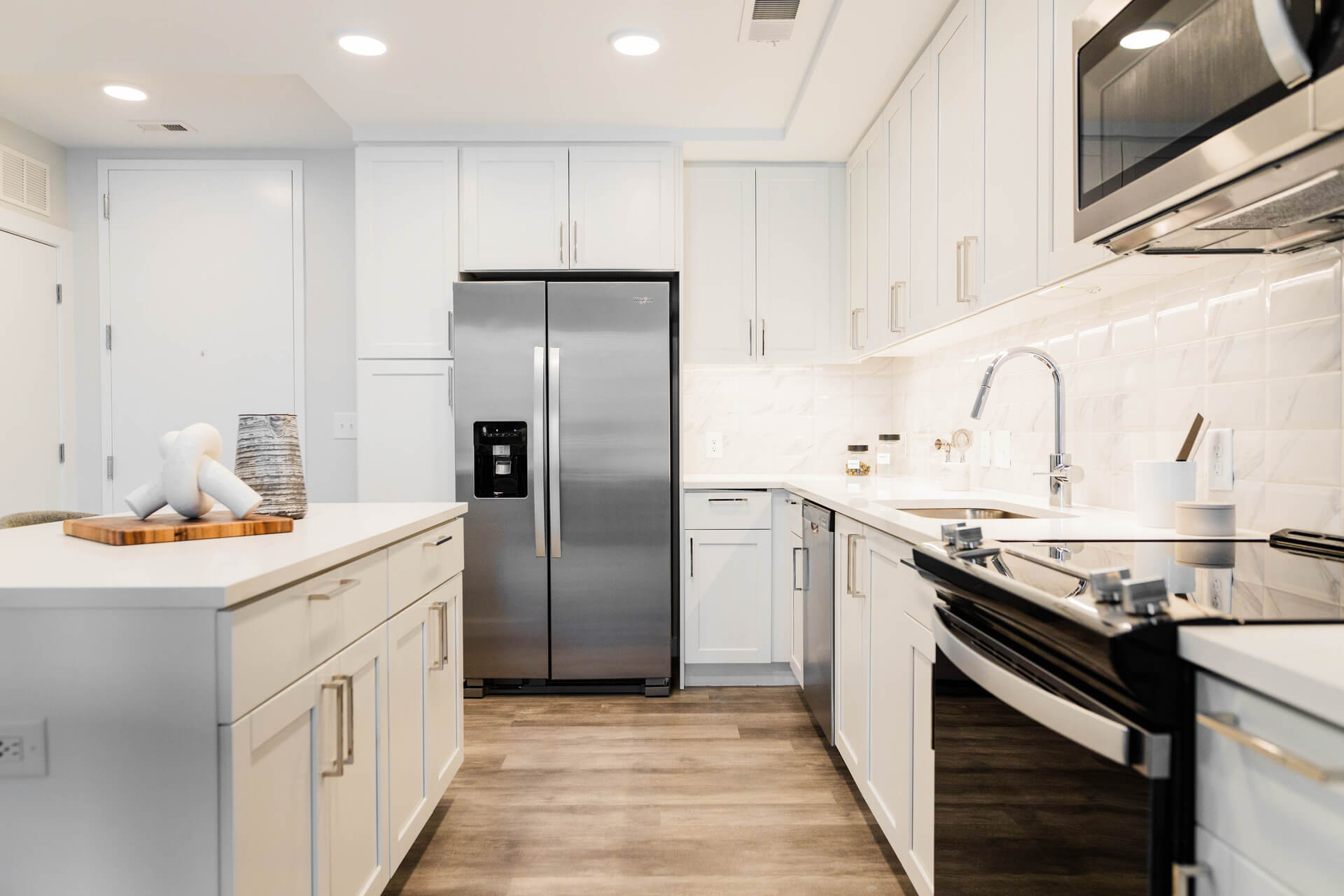 Gourmet Kitchen And Dining Area With White Countertops, Pearl Paneled Cabinets, And Stainless Steel- Appliances
