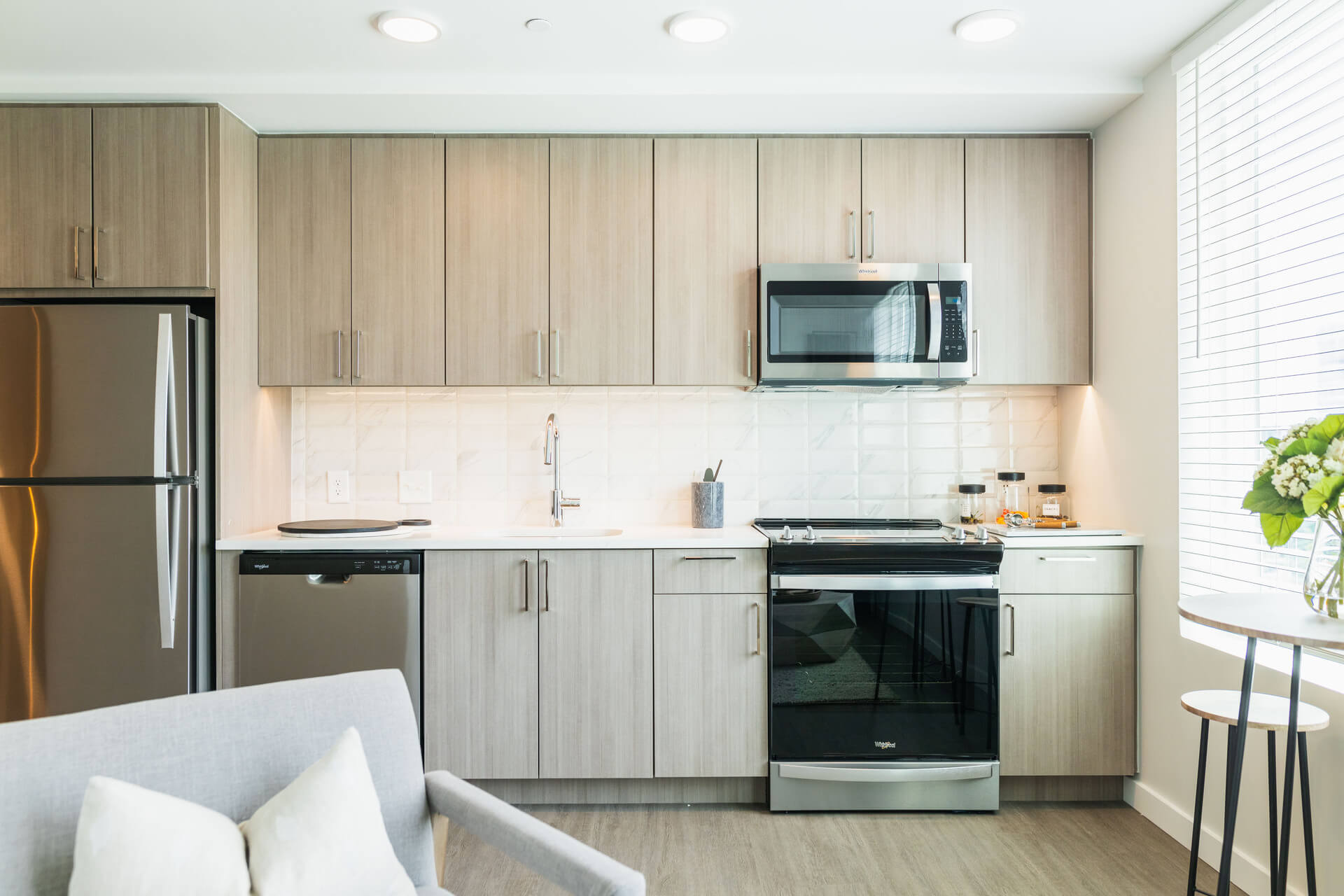 Gourmet Kitchen And Dining Area With White Countertops, Rustic Taupe Cabinets, And Stainless Steel- Appliances
